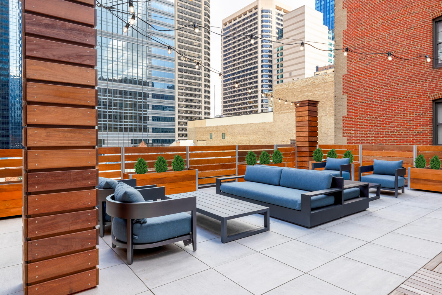The Sansom's new rooftop lounge with comfortable seating, string lights, and views of Philadelphia