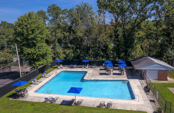 aerial view of pool with blue umbrella tables and chairs 