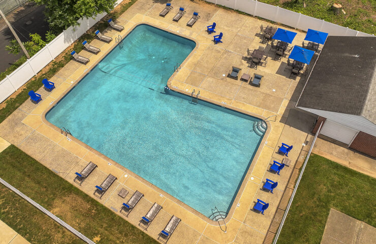 aerial view of pool with blue umbrella tables and chairs 