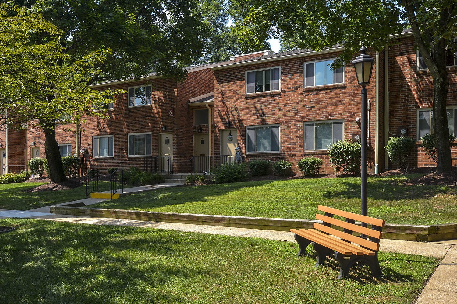 open green grass area with a bench outside apartment entrances 