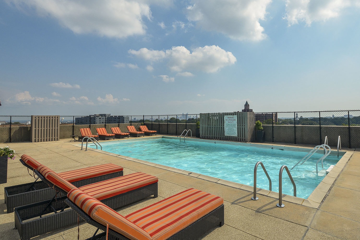 large rooftop pool with padded lounge chairs 