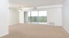 large carpeted living and dining area with access to balcony 