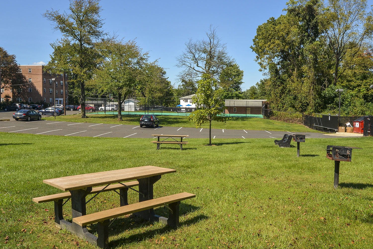 picnic tables and grills by the pool and sports court