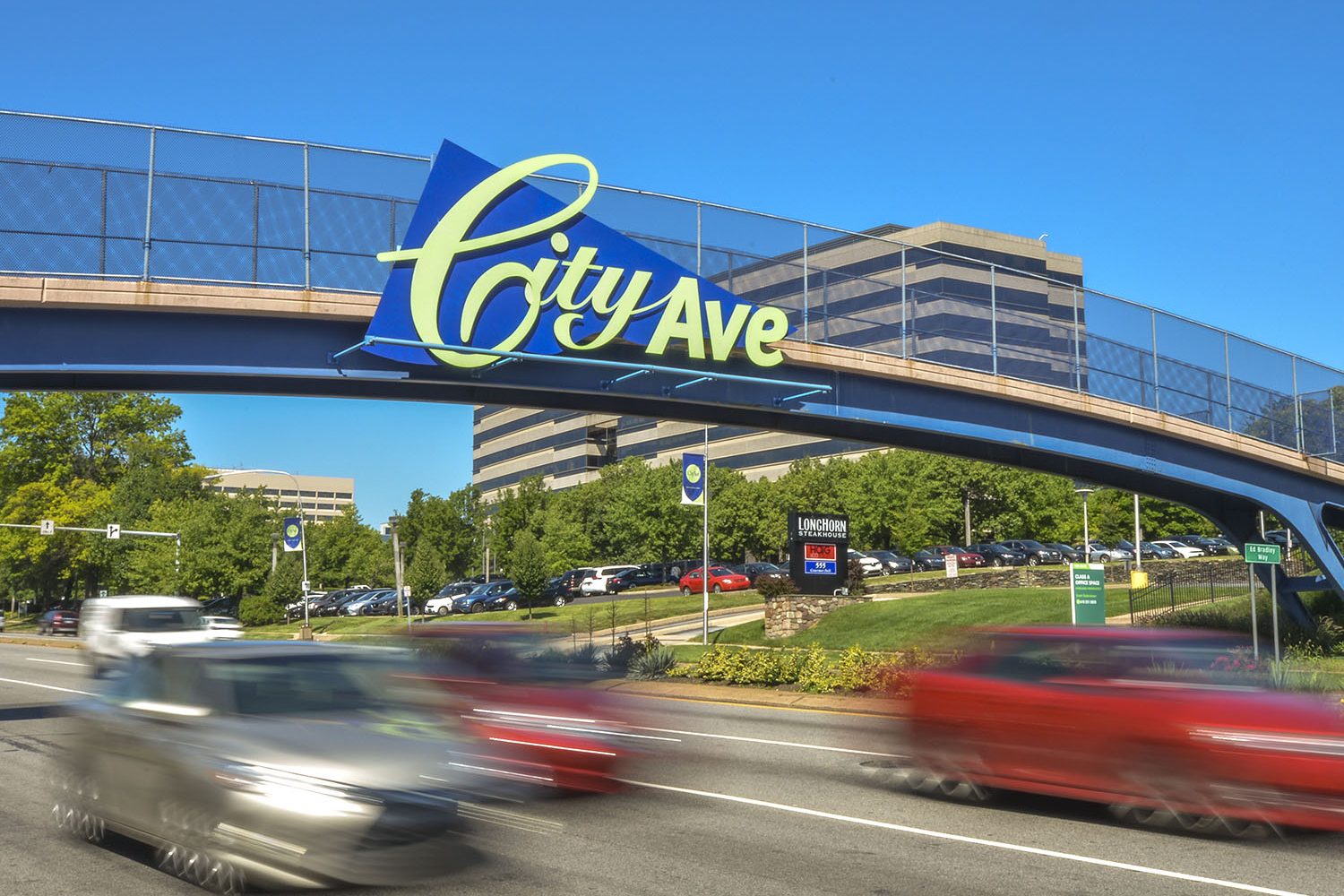 photo of cars driving under the City Ave sign on bridge 