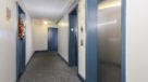 elevators and hallway with blue doors to enter apartment homes
