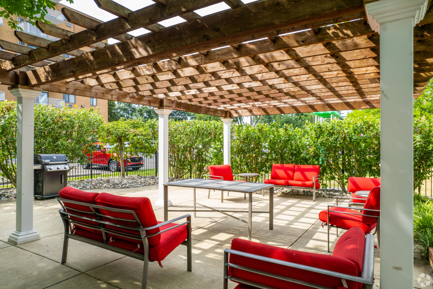 poolside pergola with red padded chairs 