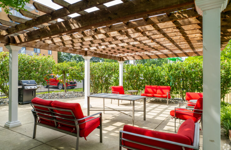 poolside pergola with red padded chairs 