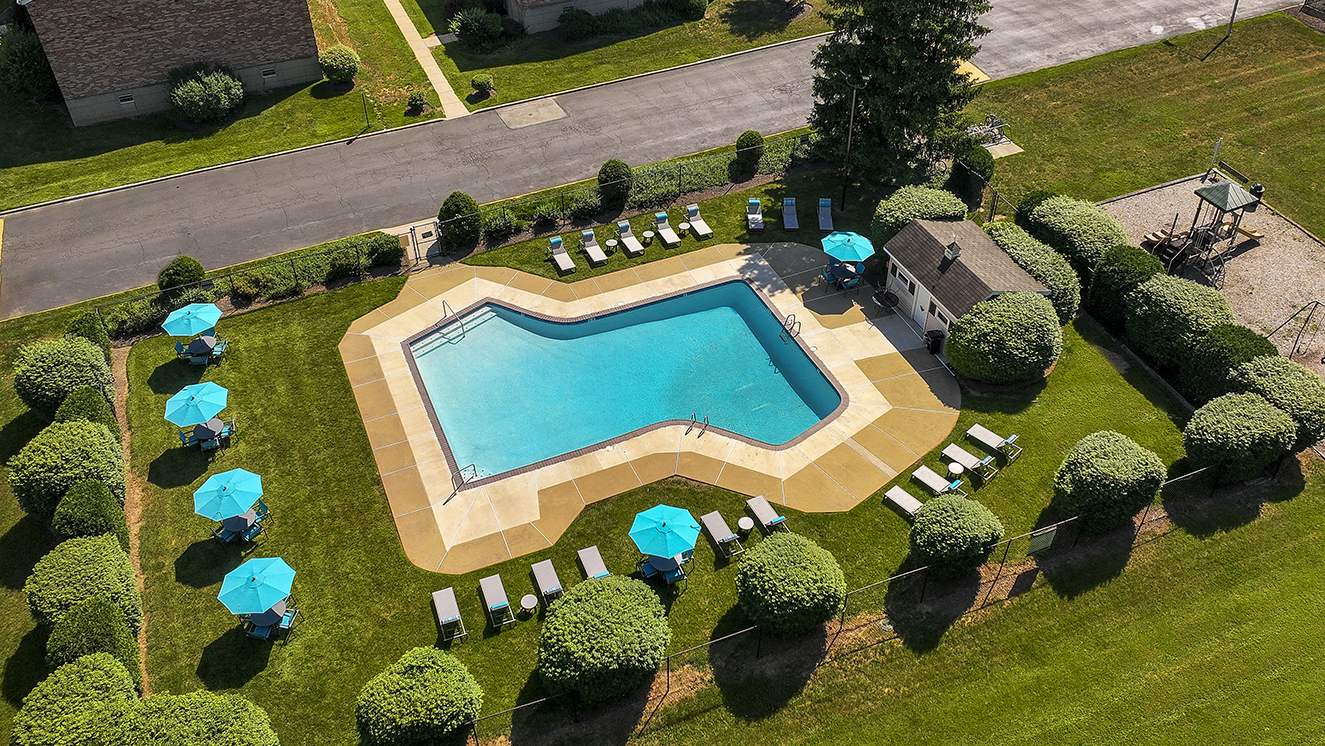 aerial view of outdoor pool with apartment in background