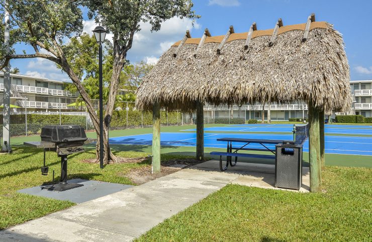tiki hut with grill and picnic table by the tennis courts