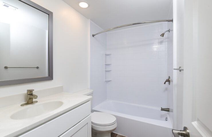 bathroom with plank flooring and tiled tub