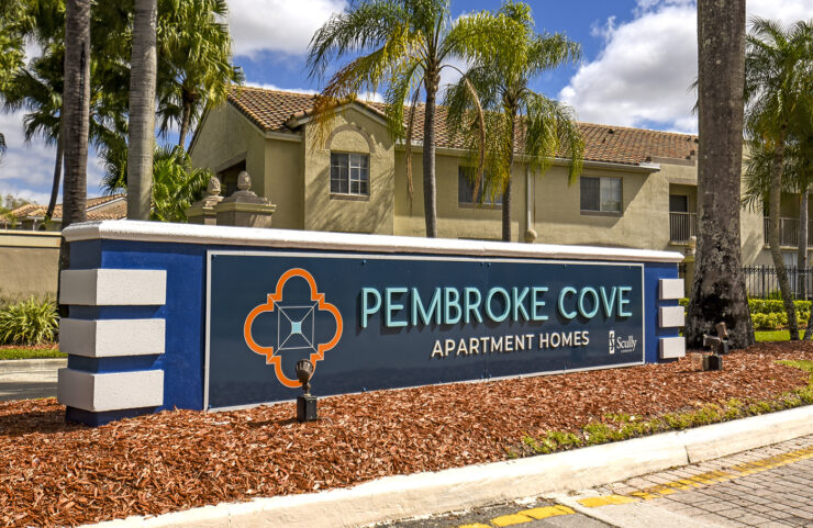 Pembroke Cove signage with palm trees behind it