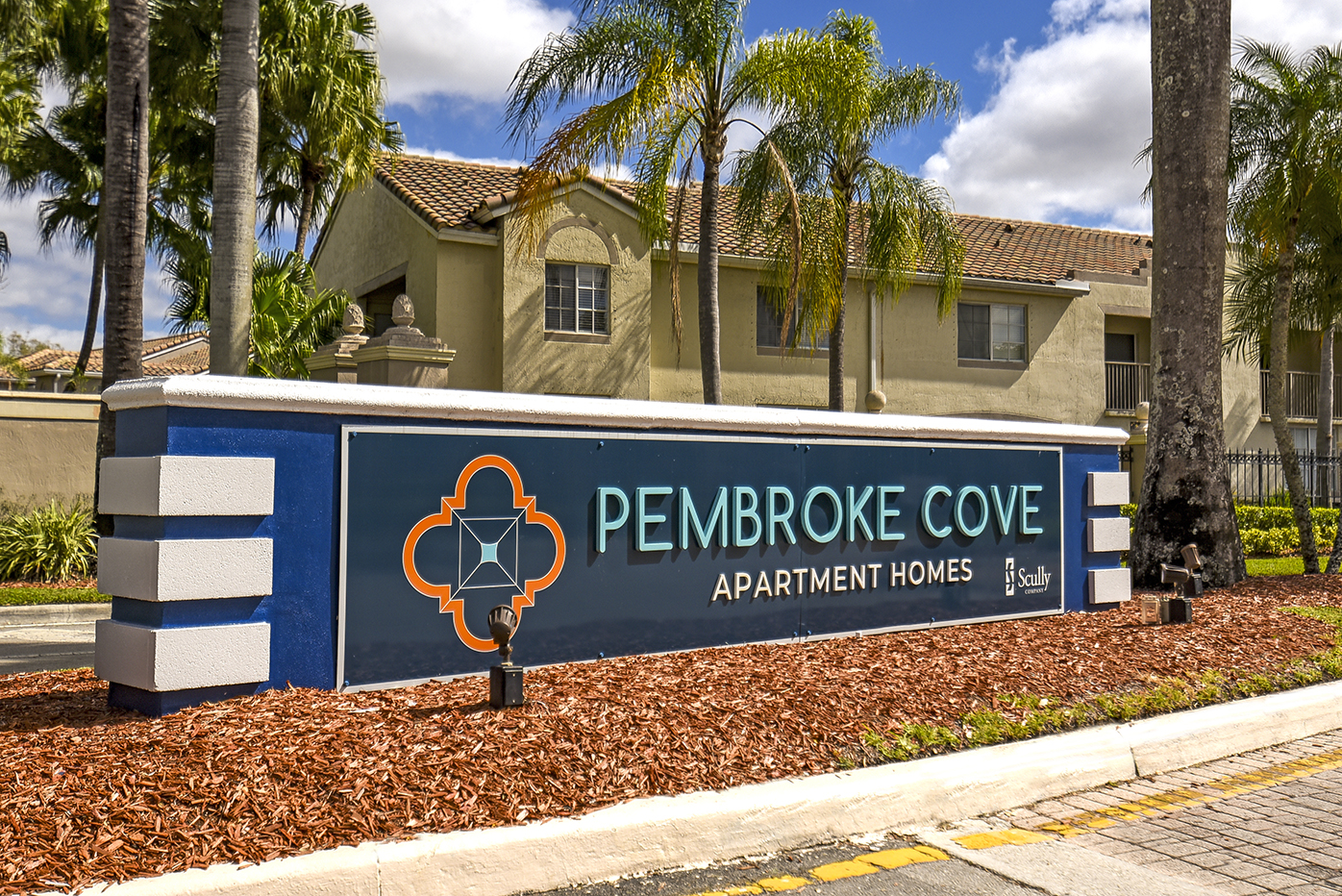 Pembroke Cove signage with palm trees behind it