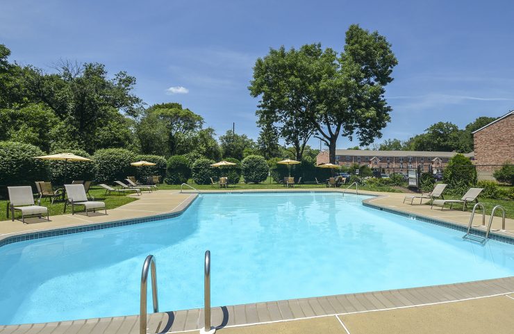 outdoor pool surrounded by lounge chairs and tables 