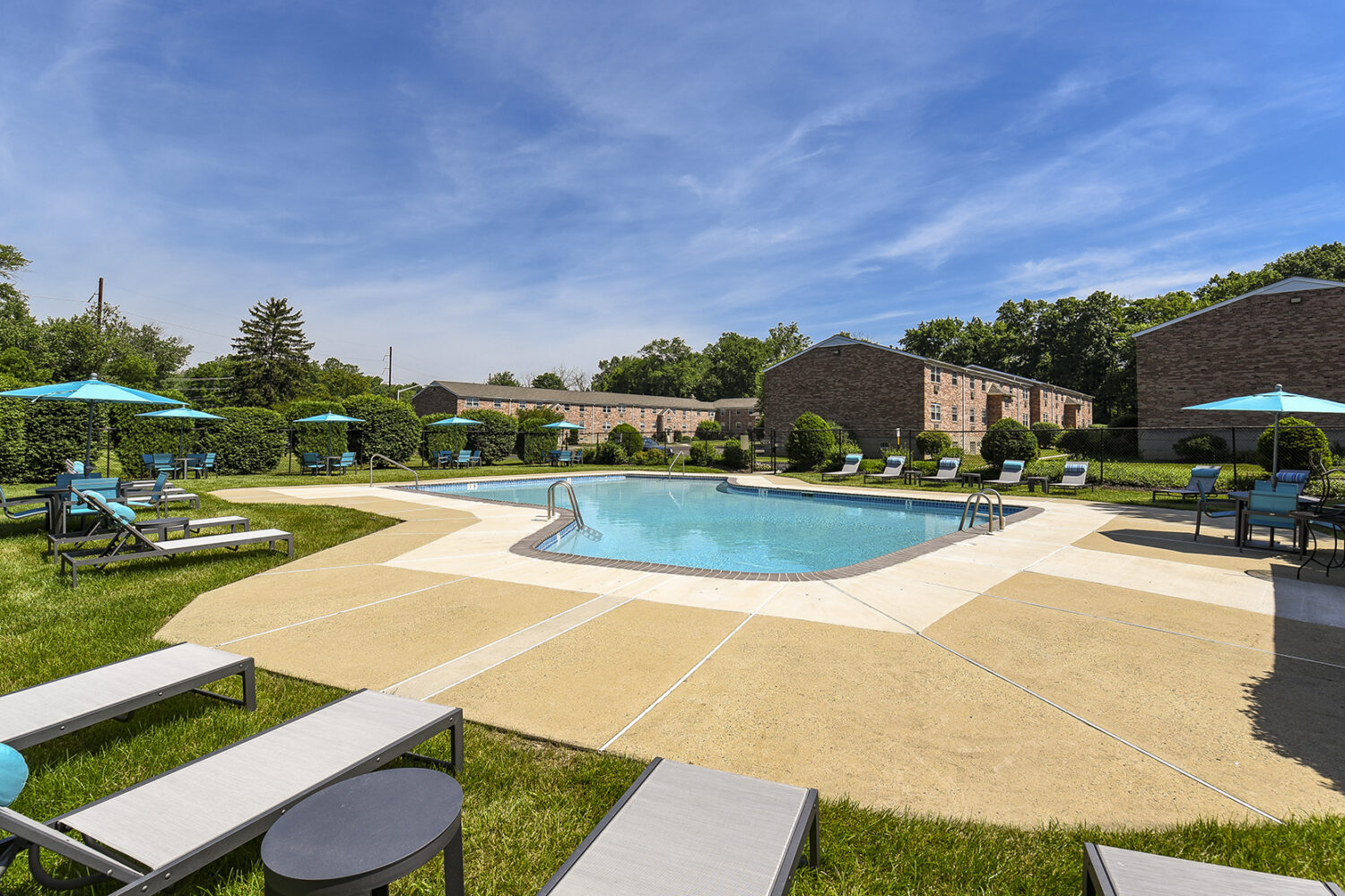 outdoor pool with lounge chairs and umbrella tables around
