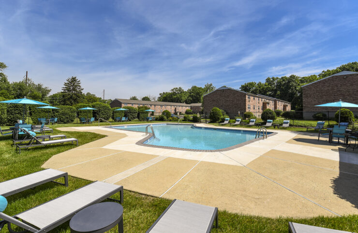outdoor pool with lounge chairs and umbrella tables around