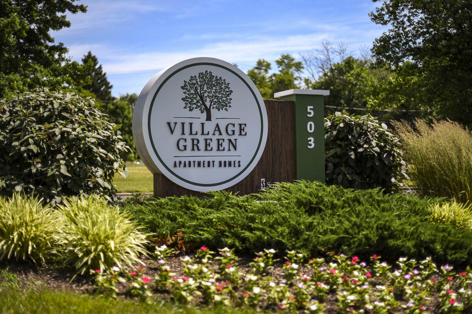 Village Green signage surrounded by shrubs and flowers