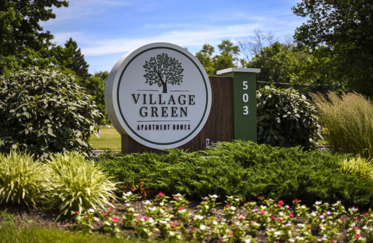 Village Green signage surrounded by shrubs and flowers