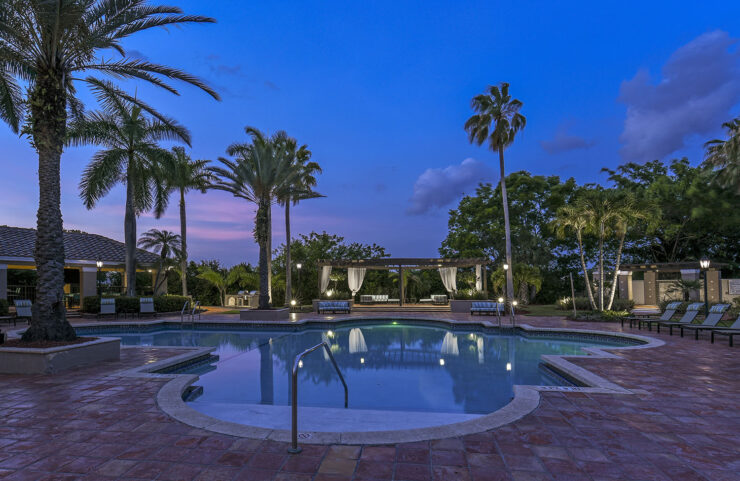 Pool at dusk with palm trees and cabana views.