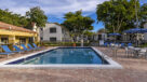 heated pool and pool deck with lounge chairs and umbrella tables