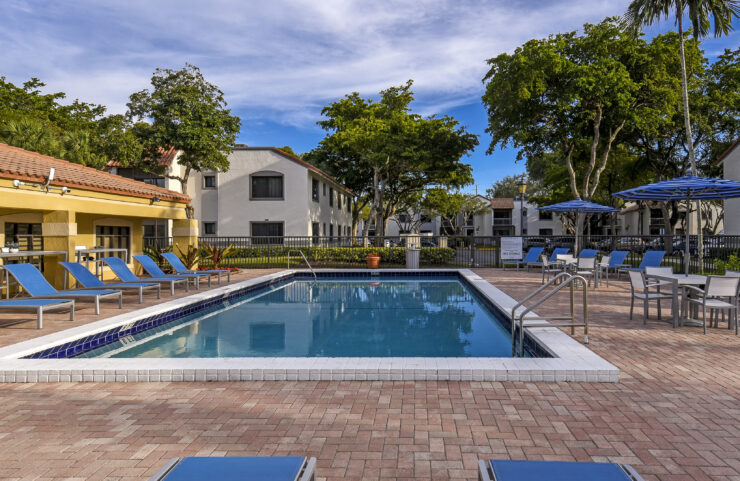 heated pool and pool deck with lounge chairs and umbrella tables