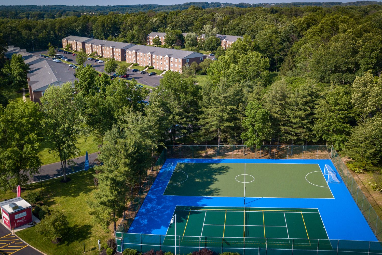 aerial view of sports court, lush trees and apartments