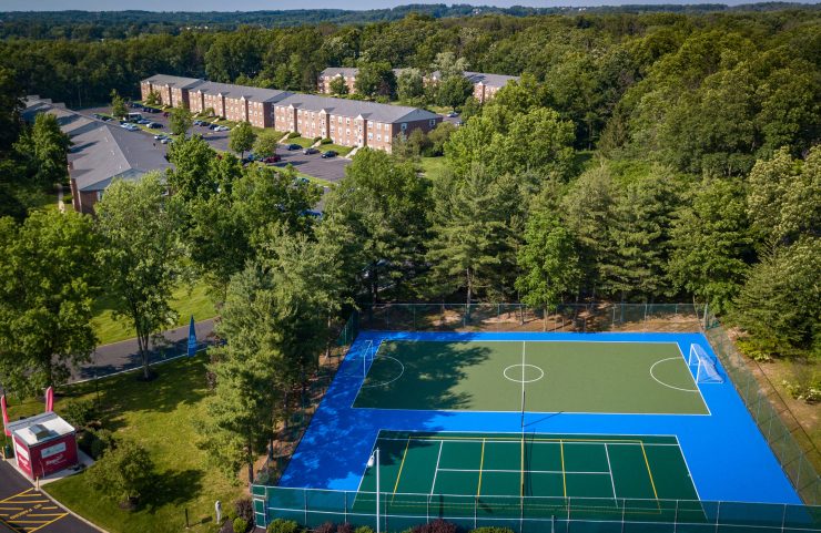 aerial view of sports court, lush trees and apartments