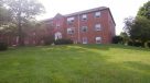 exterior shot of building surrounded by green grass and trees 