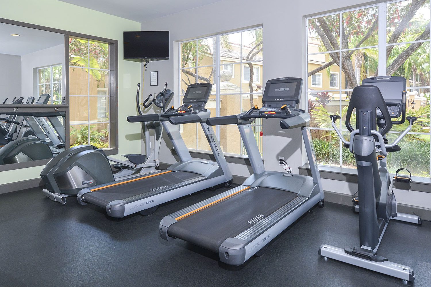 fitness center with one elliptical, two treadmills and a bike facing the window