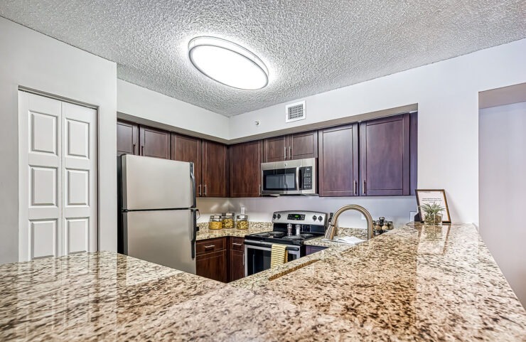 open kitchen with dark wood carbinets and stainless steel appliances