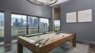 billiards table surrounded by large windows with a view of center city 
