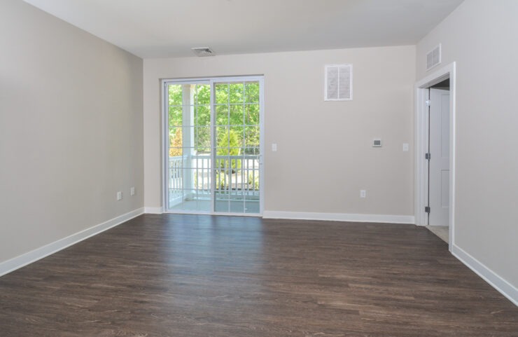 living room with plank flooring and sliding doors leading out to the balcony 