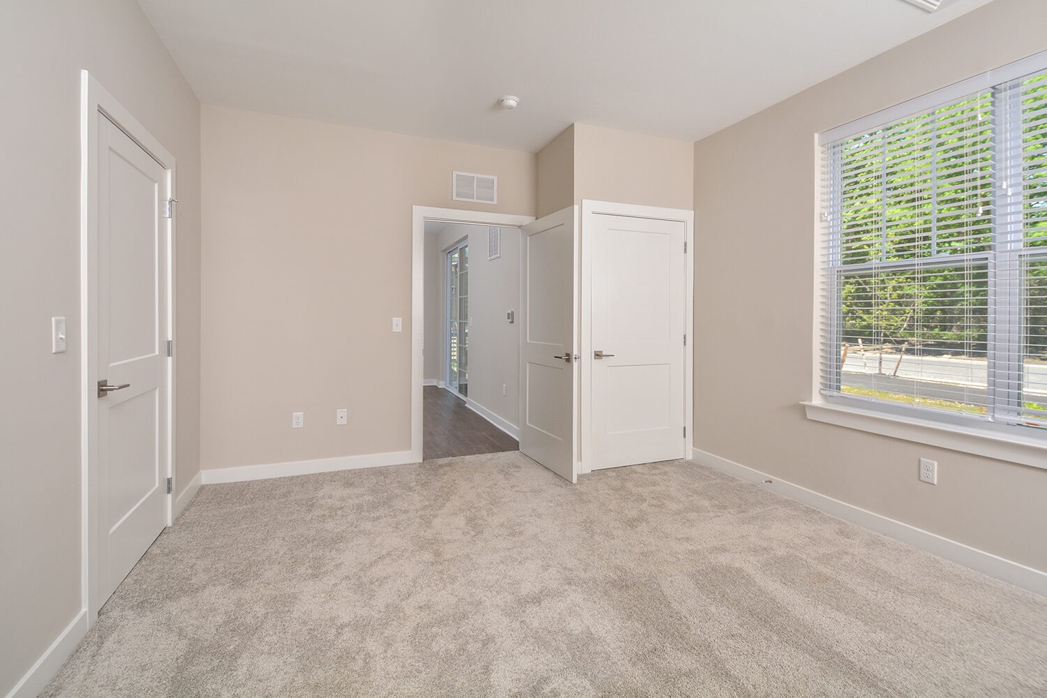 master bedroom with large window and neutral carpet
