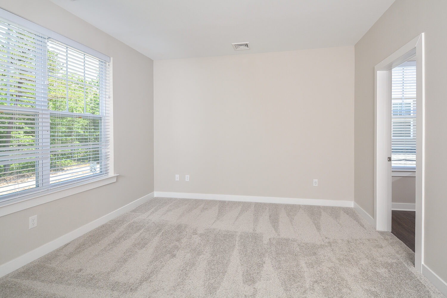 bedroom with large window and neutral color carpet