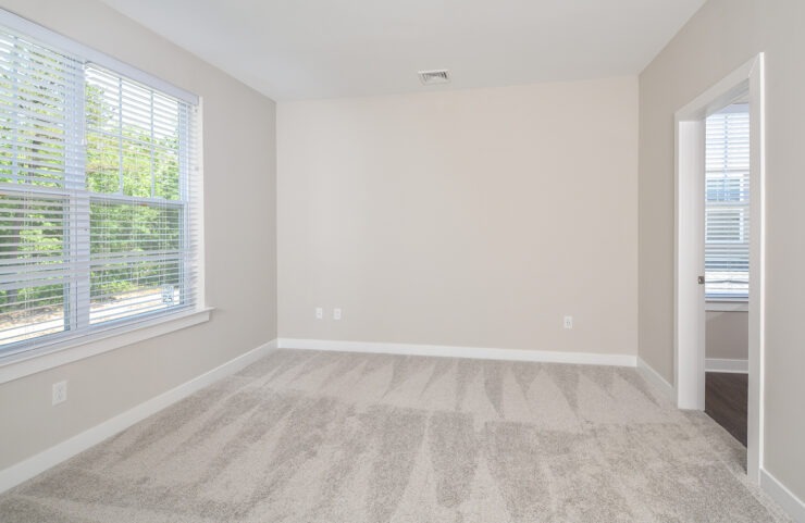 bedroom with large window and neutral color carpet