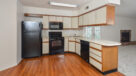 standard kitchen with black appliances and plank flooring