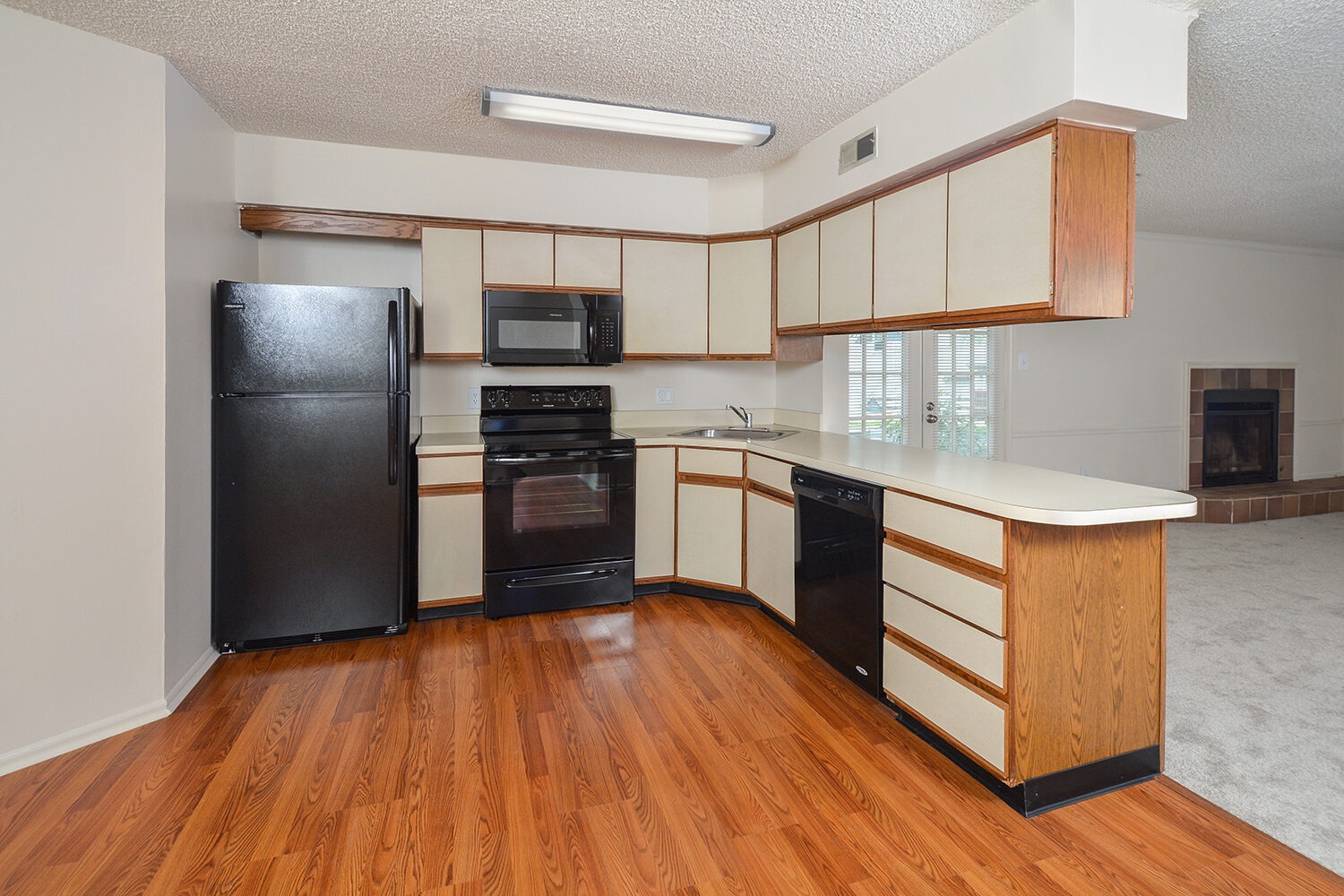 standard kitchen with black appliances and plank flooring