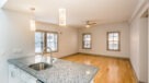 Granite Kitchen Island, Decorative Overhead Light Fixtures and Ceiling Fan In Open Layout