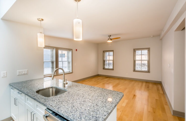 Granite Kitchen Island, Decorative Overhead Light Fixtures and Ceiling Fan In Open Layout