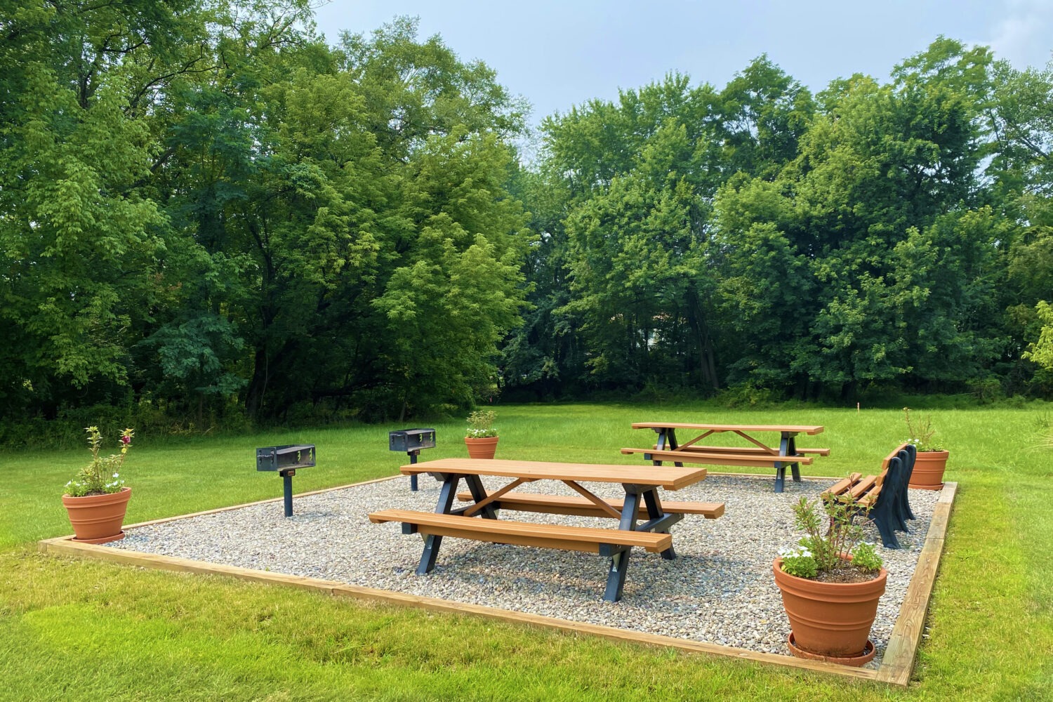 large grassy area with picnic tables and grills
