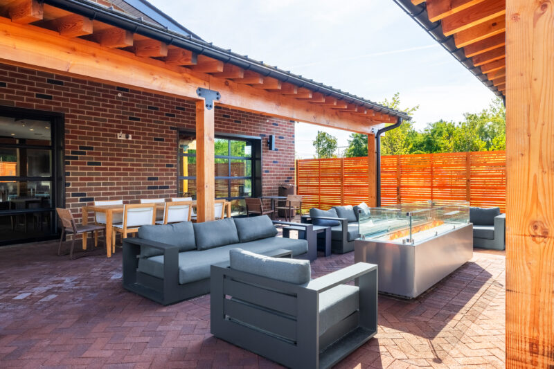 Partially covered patio complete with grilling stations, tv lounge seating, dining space, fire pits, and warm bistro lighting