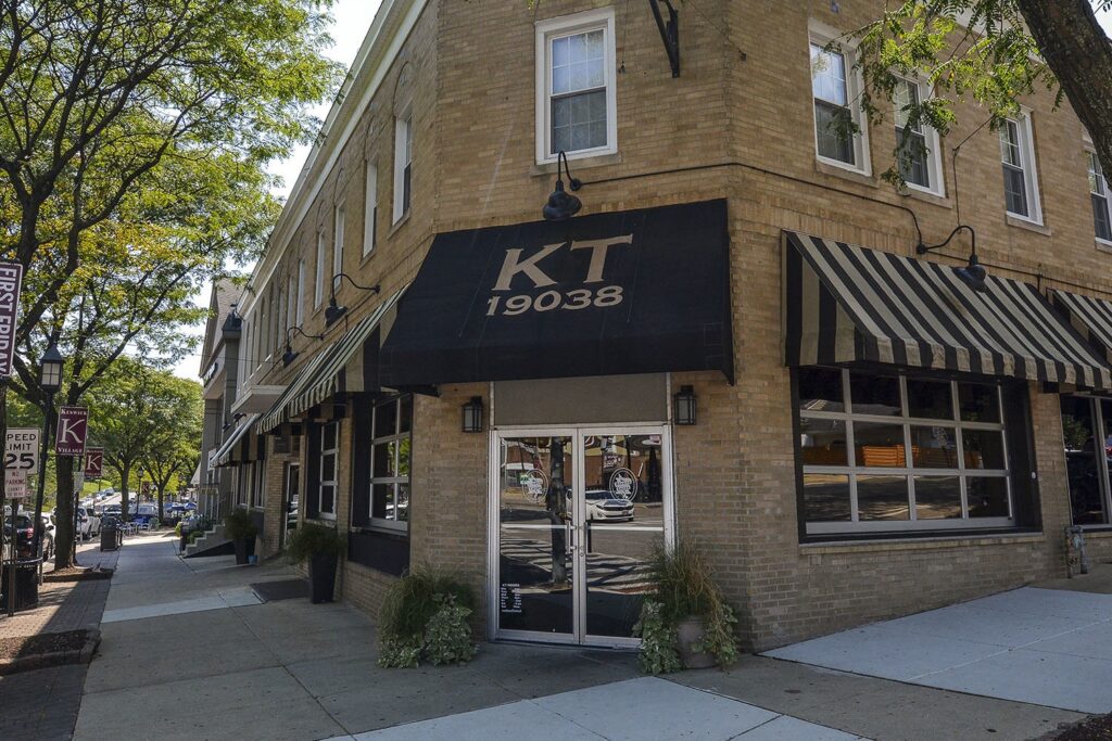 Outside of the Keswick Tavern, a tan brick building with a black awning and the words "KT 19038" printed on it