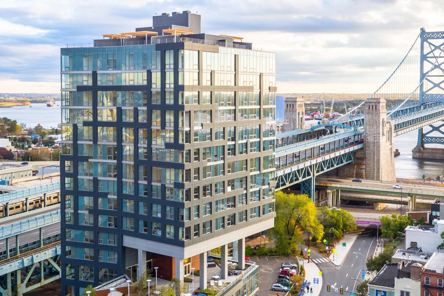 Aerial view of Bridge on Race. A sleek, glass building right on the waterfront across from the Ben Franklin Bridge