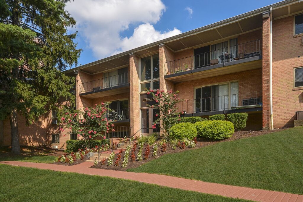 Falls Village apartment building surrounded by green trees and green grass