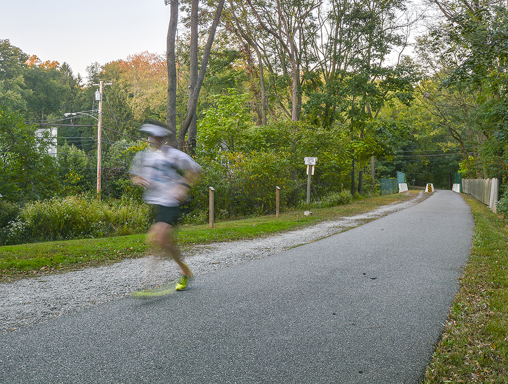 An image of the Radnor Trail, just behind Radnor Crossing Apartments. A person is running on the trail and slightly blurred