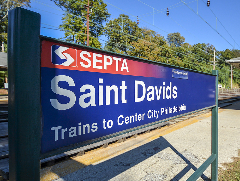 A blue SEPTA sign reading "Saint Davids" in front of train tracks leading down the Main Line