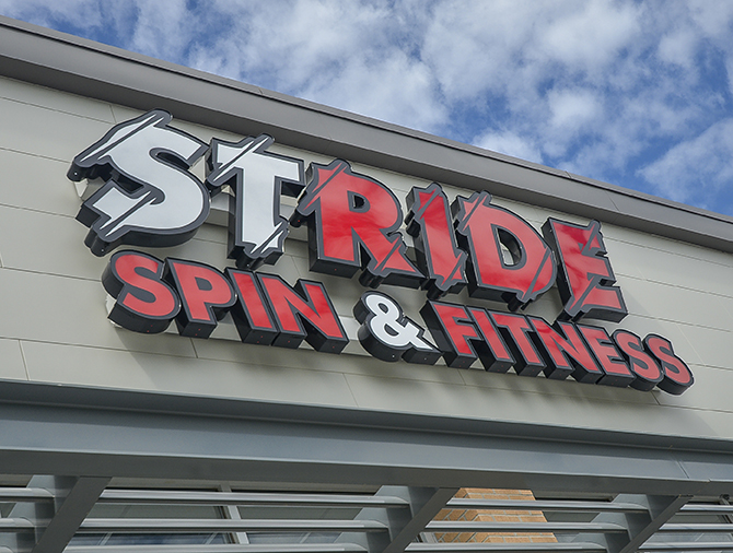 The red and white logo of a gym that reads "Stride Spin & Fitness"