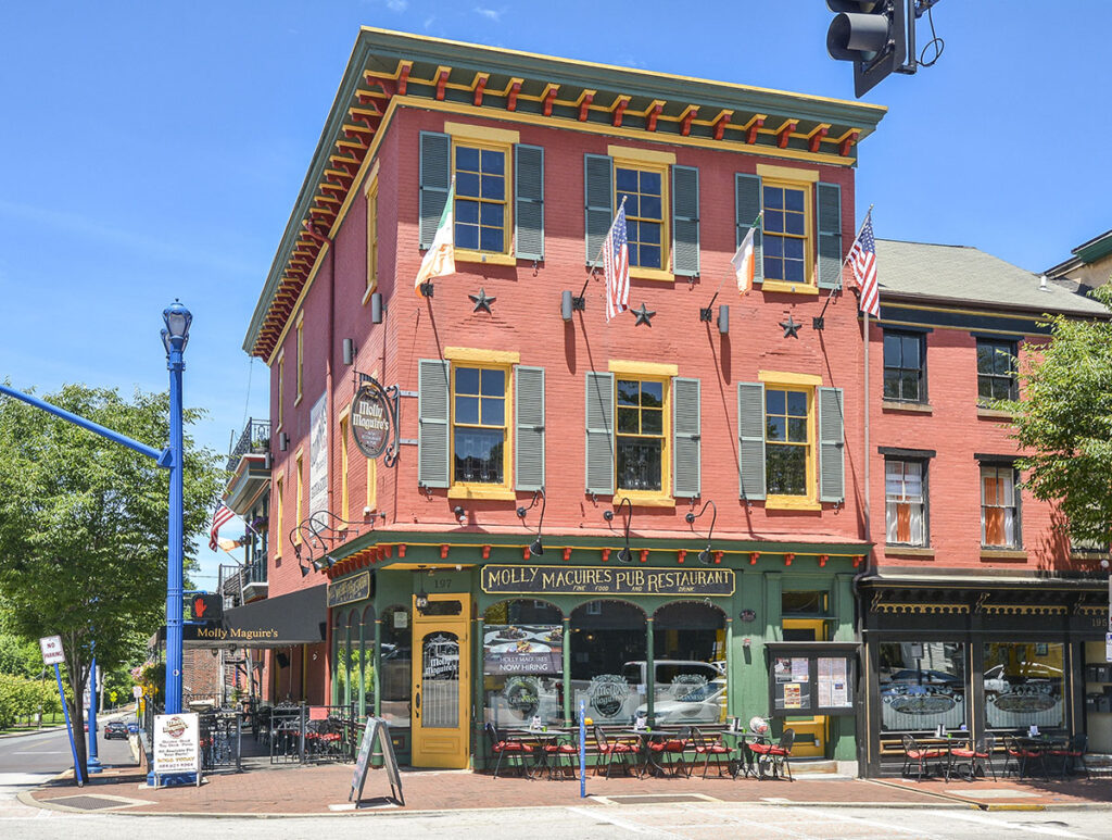 A red stone building with green trim in an Irish Pub style. Black and gold sign reads "Molly Maguire's Pub and Restaurant."