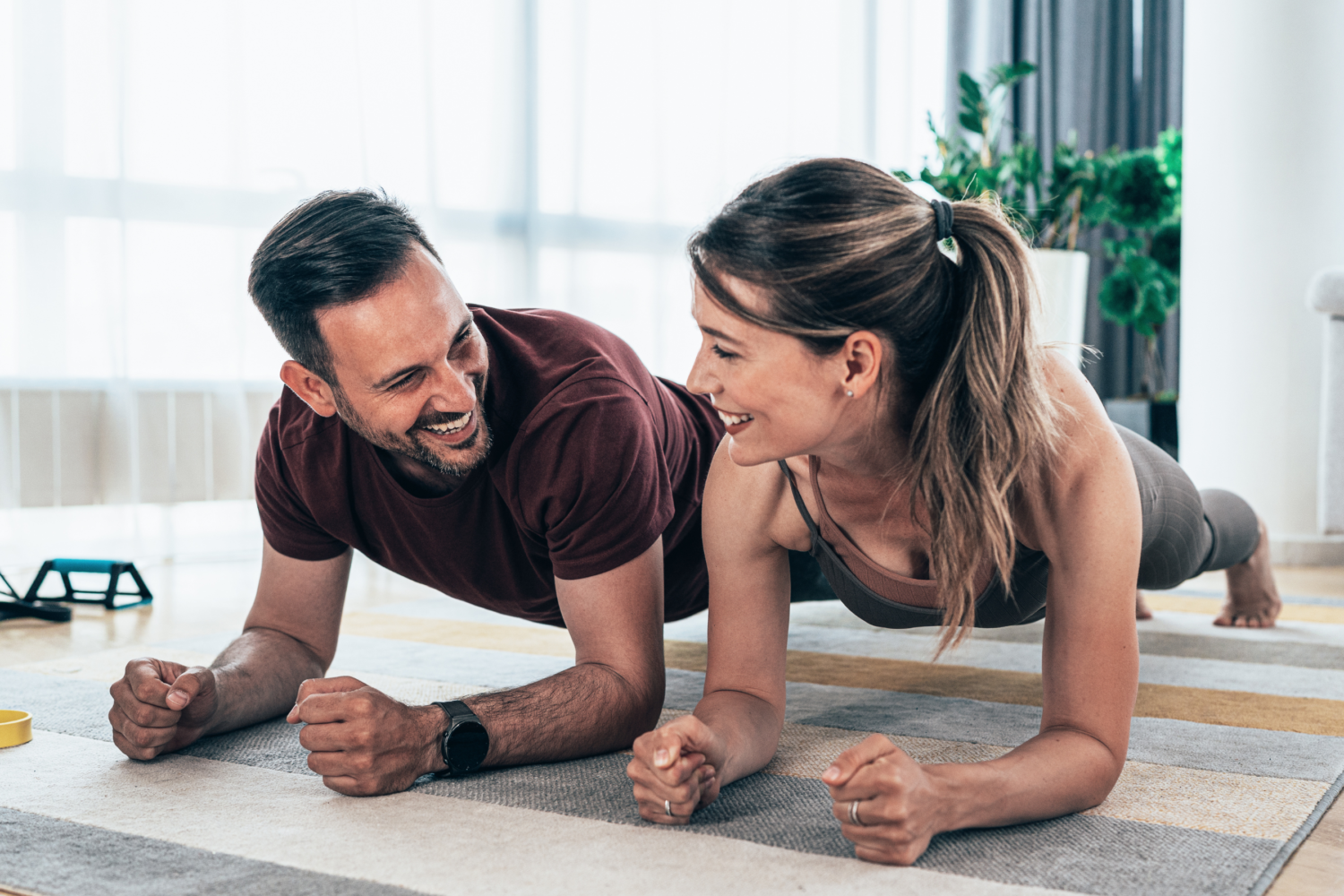 Two people working out doing planks and smiling at each other