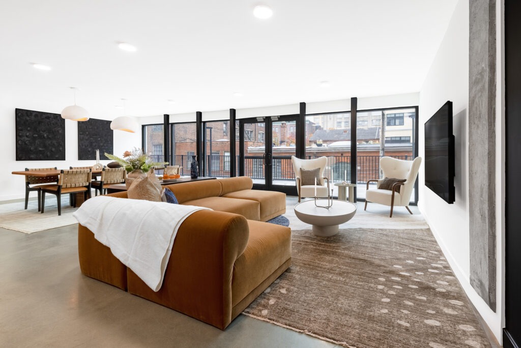 Resident lounge with large comfortable couch, televisions, and many floor-to-ceiling windows