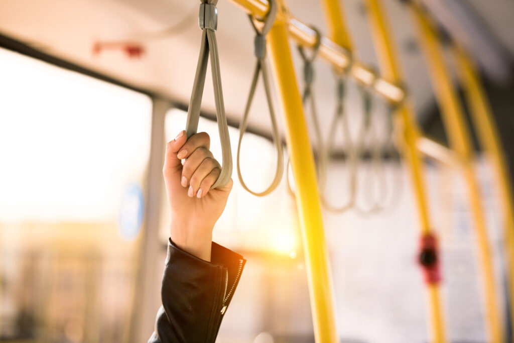 Woman's hand holding handles on a public bus with yellow poles
